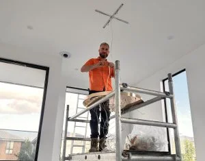 • Electrician inspecting old cloth-covered wiring in a Sydney home ceiling — a clear sign the house needs rewiring